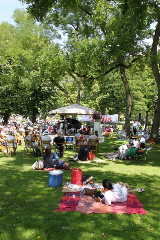 Having fun, picnic in this park with trees and many other people on chairs or cloth, enjoy the summer, stock photo