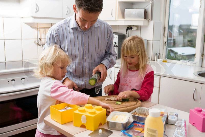 A single father preparing school lunch with his daughters, stock photo