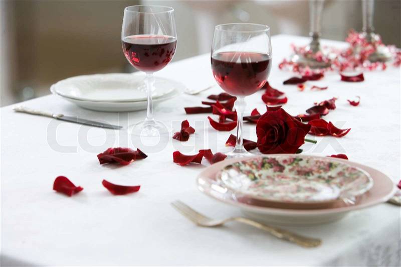 Table decorated with rose petals for a romantic dinner date, stock photo