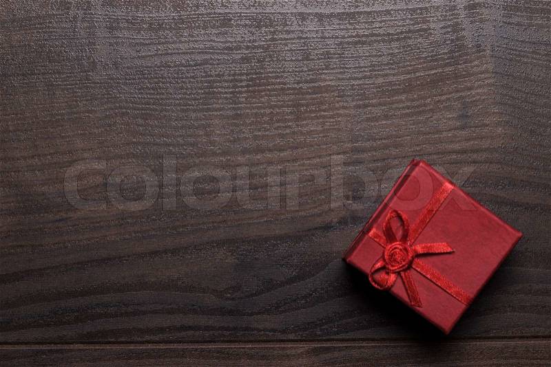 Red present box over brown wooden background, stock photo