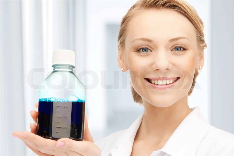 Female lab worker holding up bottle with blue liquid, stock photo