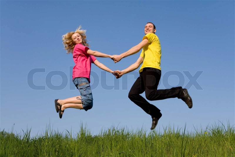 Man and girl jumping on the green meadow, stock photo