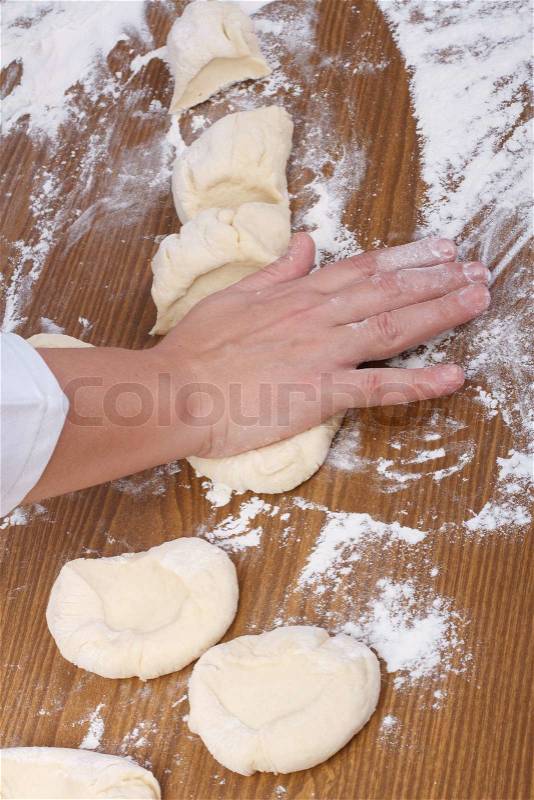 Hand baker makes flat cakes dough. Pressing, stock photo