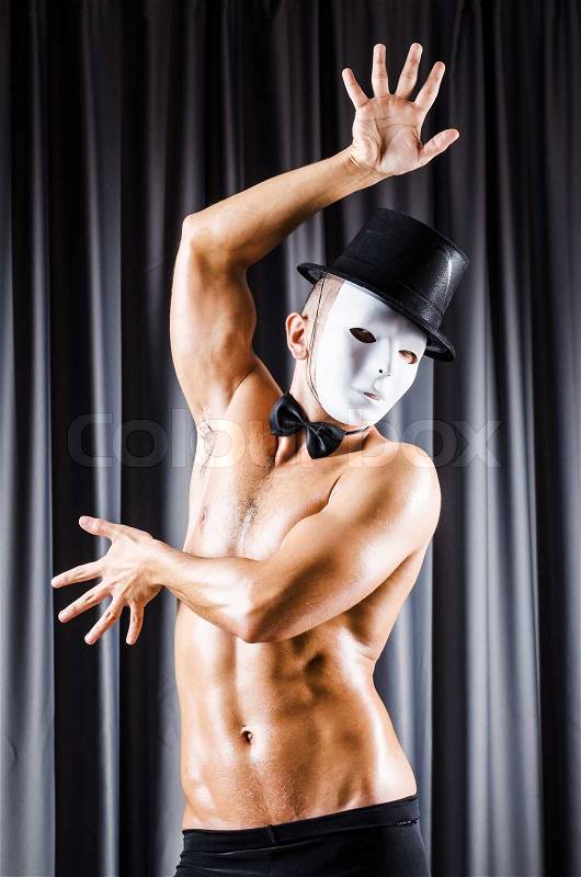 Muscular actor with mask against curtain, stock photo