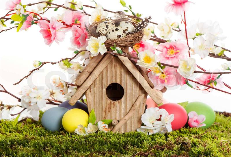 Colorful easter decoration with birdhouse and eggs on green grass. spring apple and cherry blossoming, stock photo