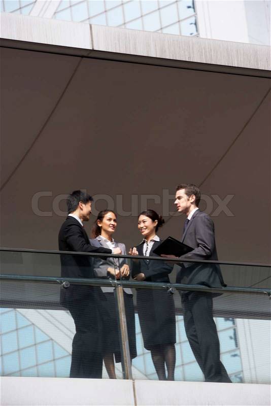 Four Business Colleagues Having Discussion Outside Office Building, stock photo
