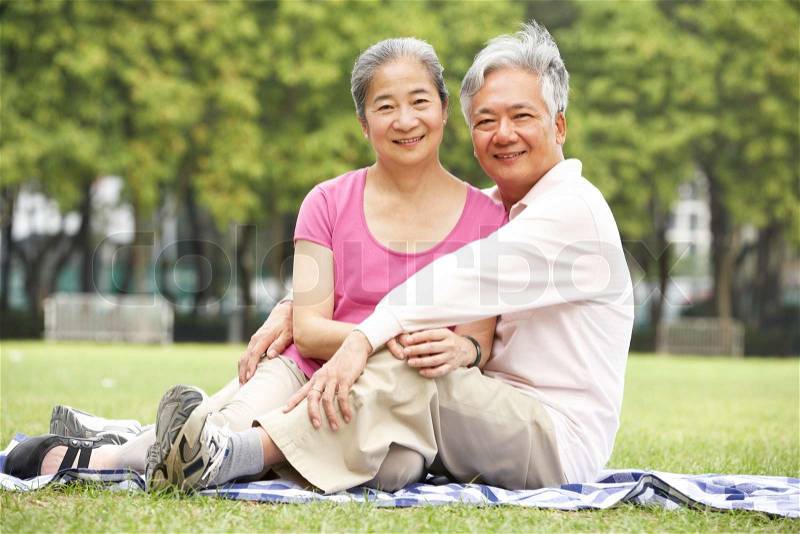 Senior Chinese Couple Relaxing In Park Together, stock photo