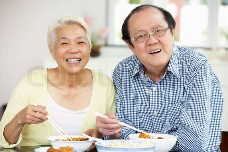 Senior Chinese Couple Sitting At Home Eating Meal, stock photo