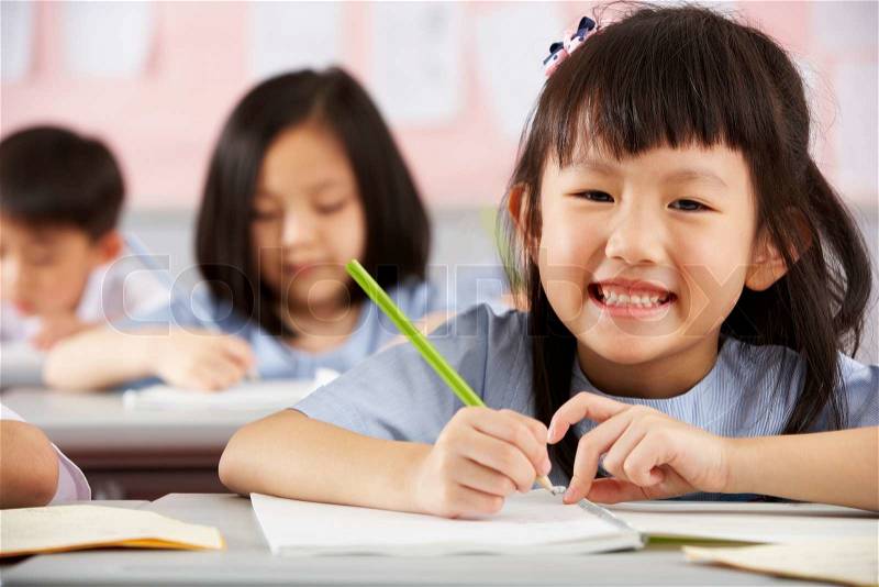 Group Of Students Working At Desks In Chinese School Classroom, stock photo
