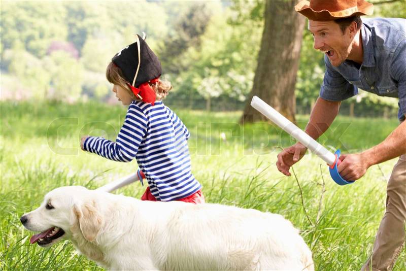 Father Playing Exciting Adventure Game With Son And Dog In Summer Field, stock photo