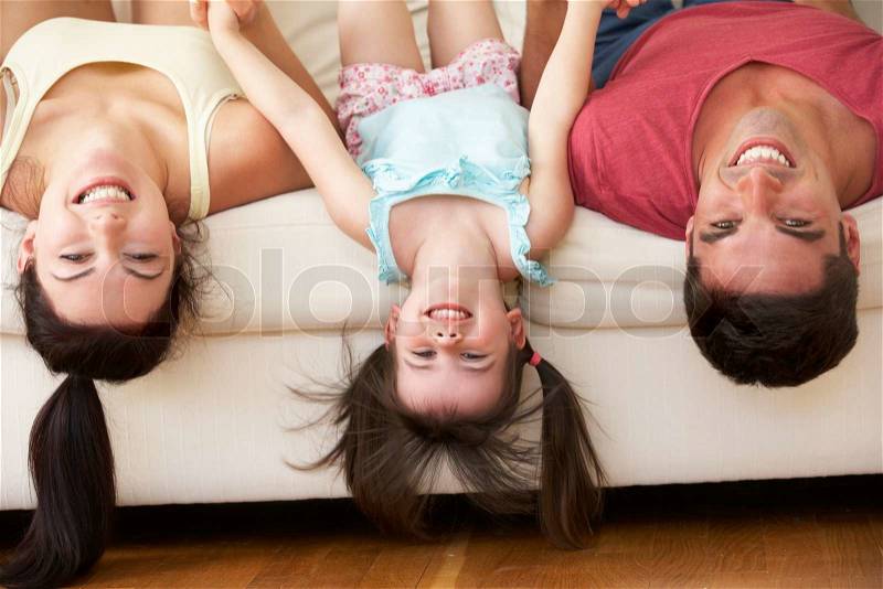 Family Lying Upside Down On Sofa With Daughter, stock photo
