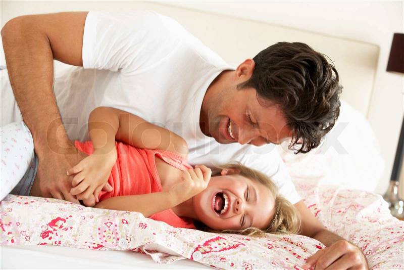 Father And Daughter Relaxing Together In Bed, stock photo