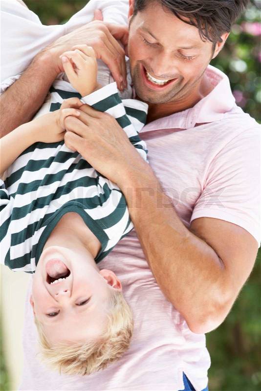 Father Holding Son Upside Down Outdoors, stock photo