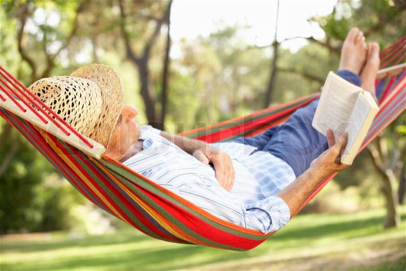Senior Man Relaxing In Hammock With Book, stock photo