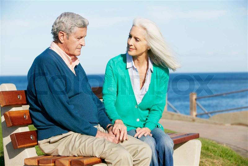 Senior Woman Comforting Depressed Husband Sitting On Bench, stock photo