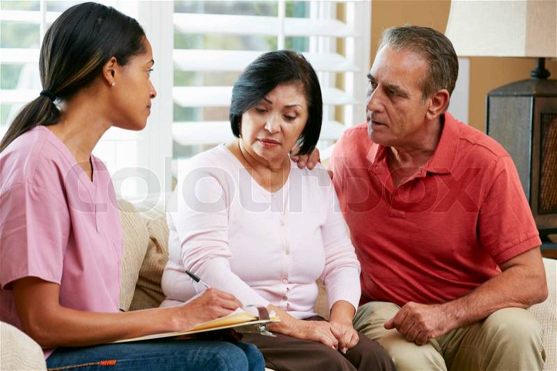 Nurse Making Notes During Home Visit With Senior Couple, stock photo