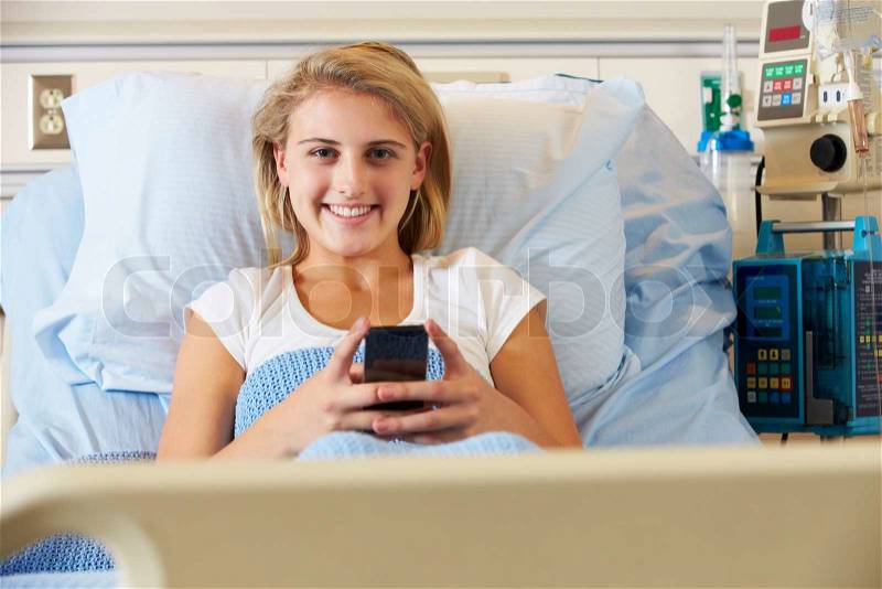 Teenage Female Patient Using Mobile Phone In Hospital Bed, stock photo
