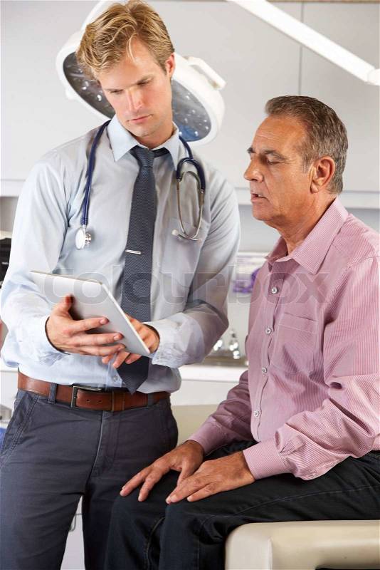 Doctor Discussing Records With Patient Using Digital Tablet, stock photo