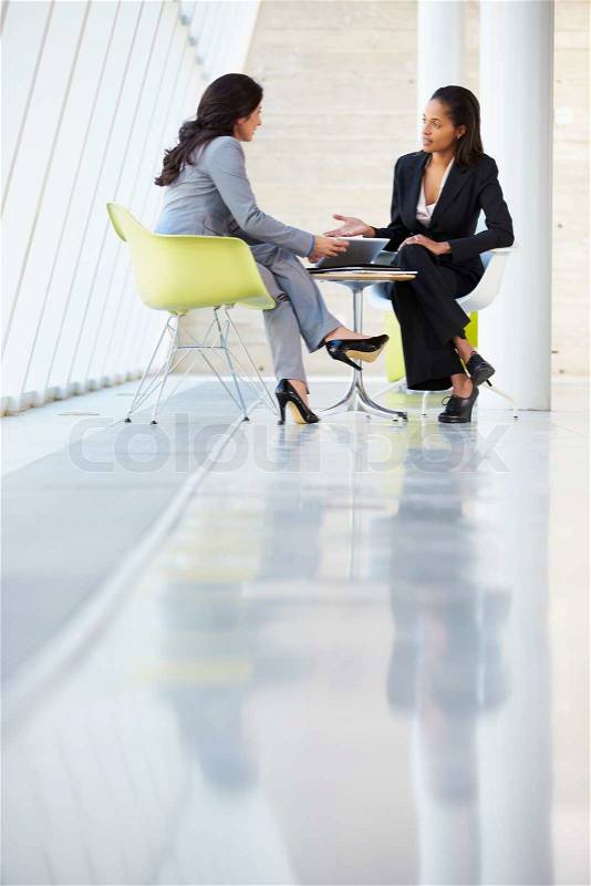 Two Businesswomen Meeting Around Table In Modern Office, stock photo