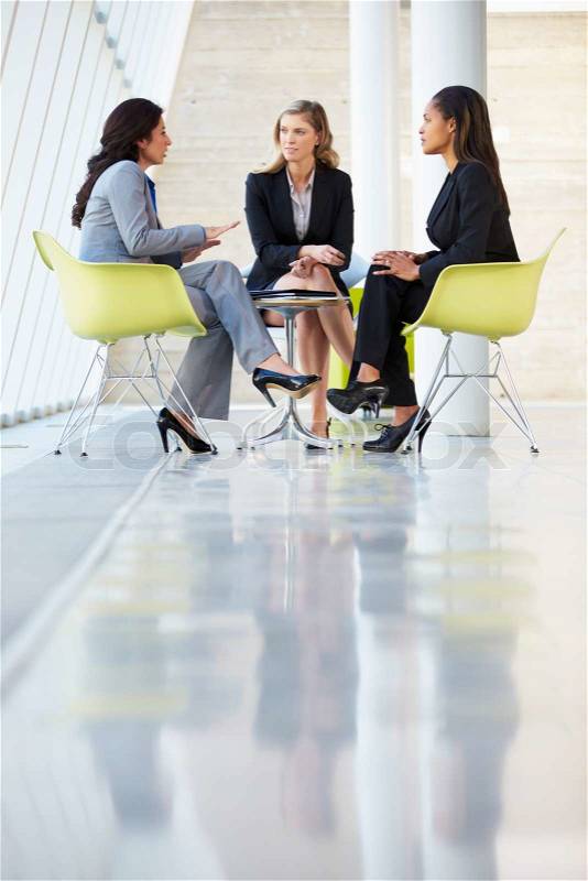 Three Businesswomen Meeting Around Table In Modern Office, stock photo