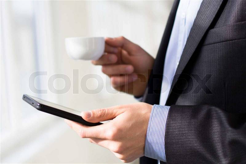 Businessman holding tablet pc and a cup of coffee, stock photo