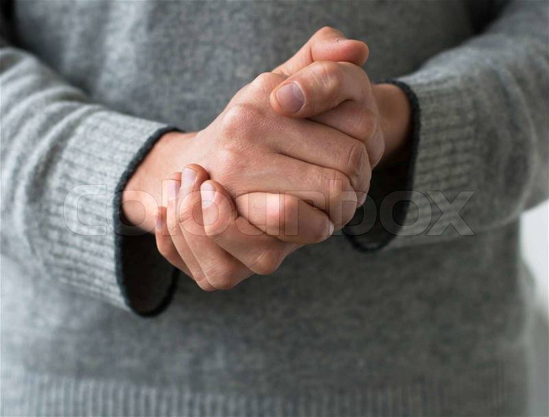 A man holds his hands folded, stock photo
