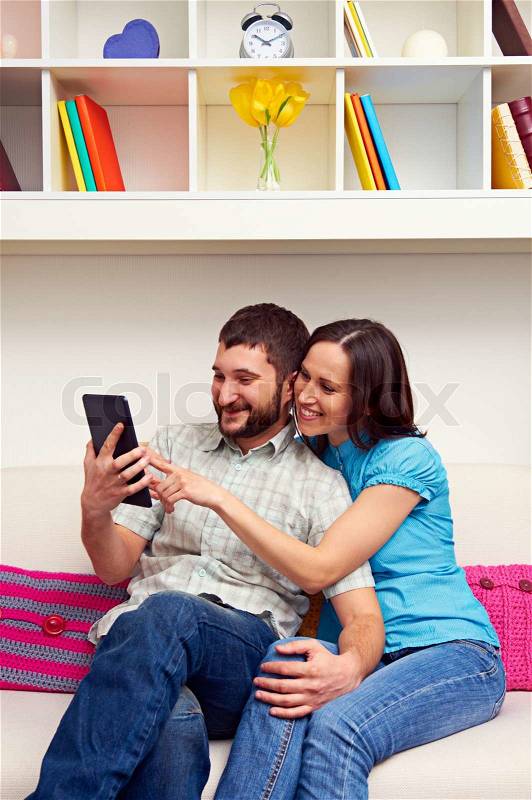 Smiley couple sitting on sofa, stock photo