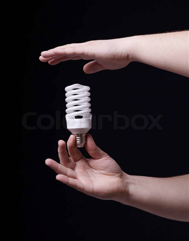 Light bulb in hand on a black background, stock photo