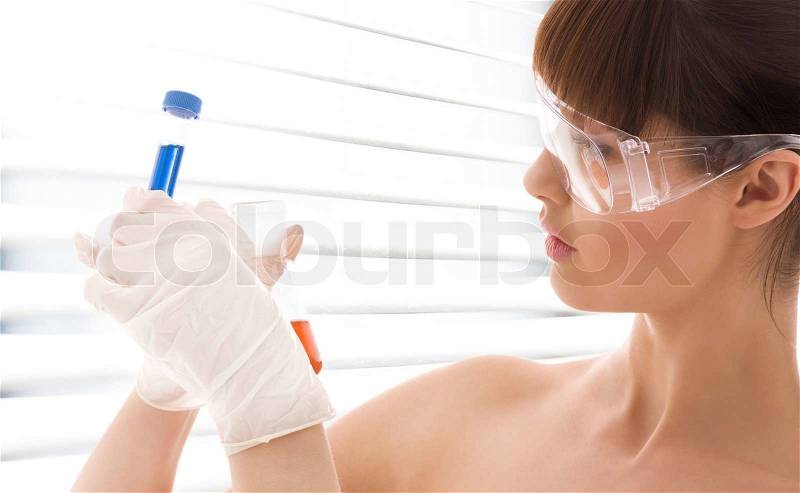 Closeup of beautiful lab worker holding up test tubes, stock photo