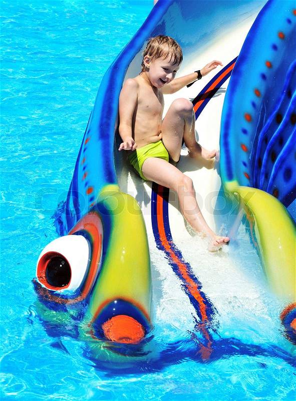 little boy sliding down a water slide and having fun, stock photo