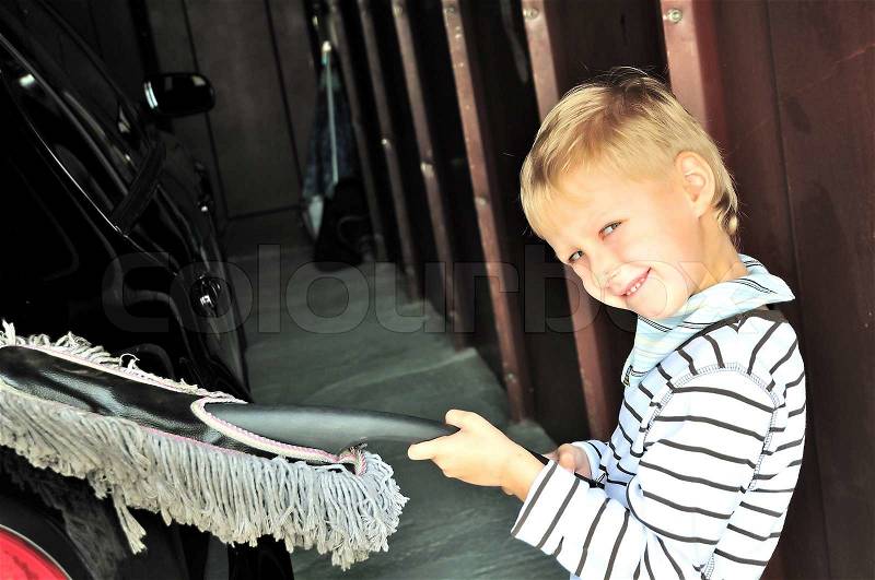 Young boy cleaning his dad\'s dark car in garage, stock photo
