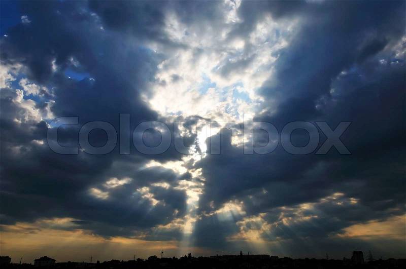 Dark clouds and little peace of blue sky with sunlight under the town, stock photo