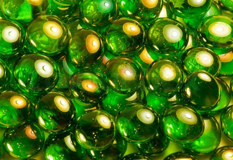 Full frame abstract background picture with iridescent green glass beads in dark back, stock photo