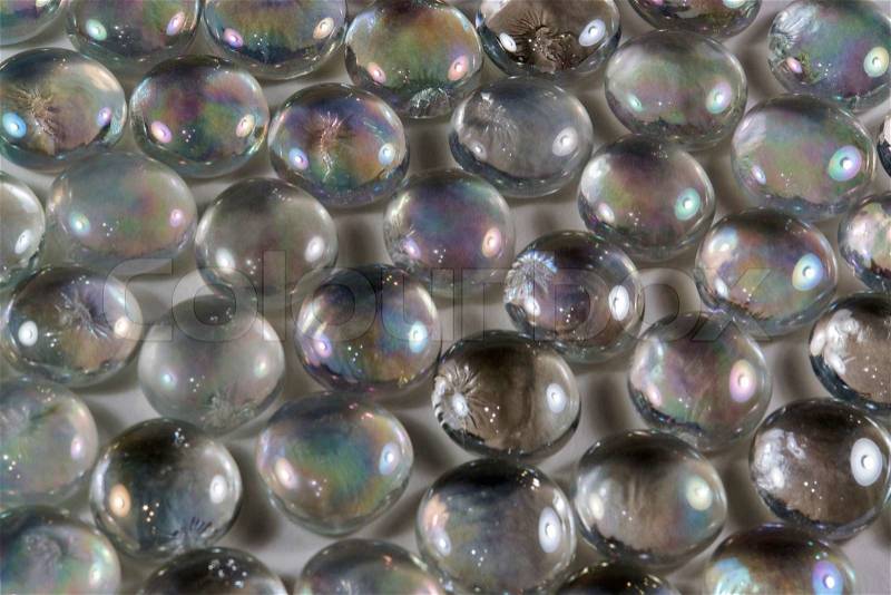 Full frame abstract background picture with iridescent glass beads in dark back, stock photo