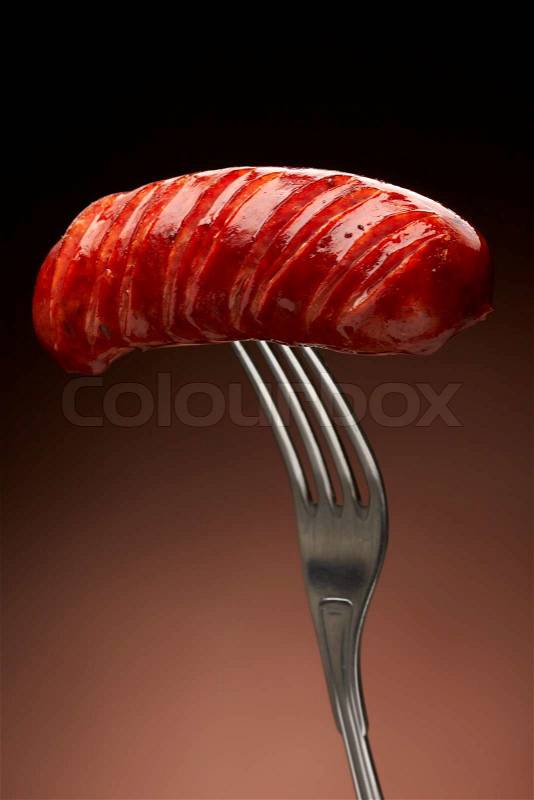 Grilled smoked sausage on a fork, stock photo