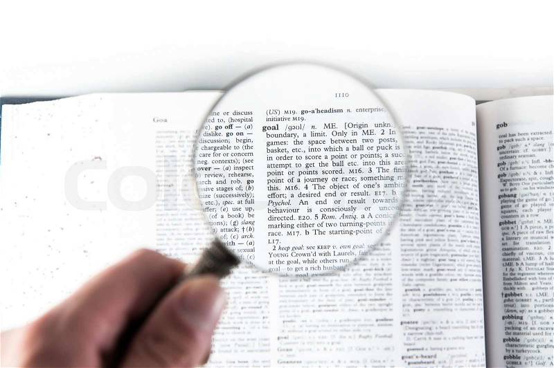 A magnifying glass on the word goal on a dictionary, stock photo