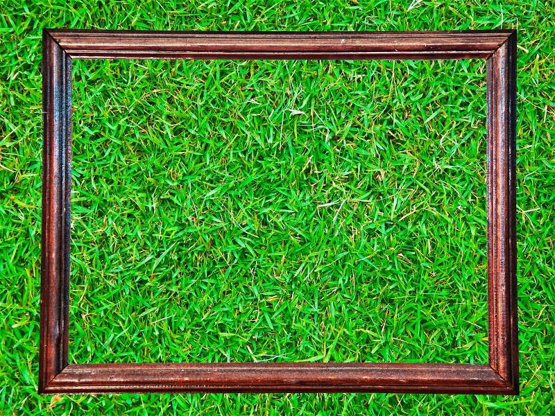 The Vintage wooden frame isolated on green grass background, stock photo