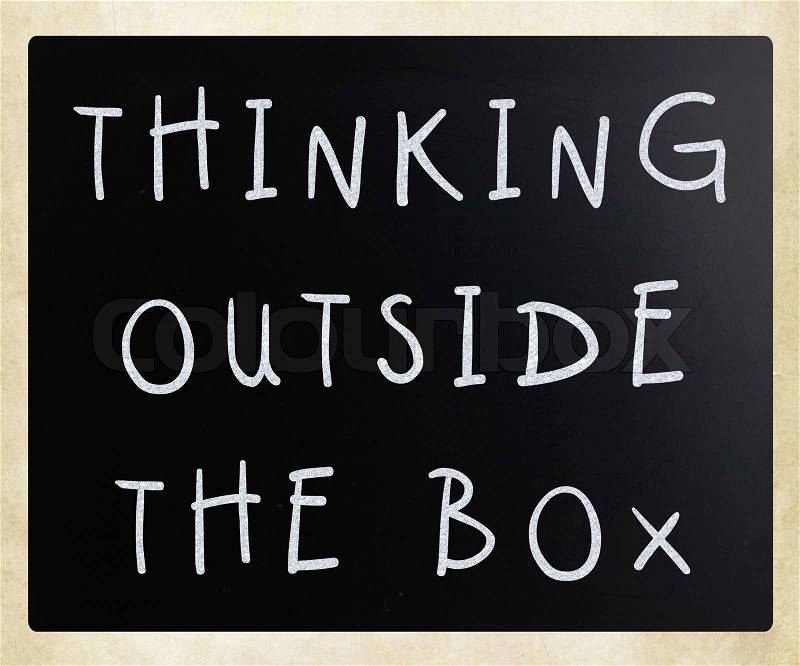 Thinking outside the box phrase, handwritten with white chalk on a blackboard, stock photo