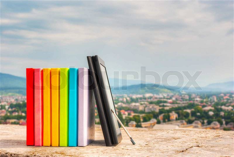 Stack of colorful books with electronic book reader, stock photo