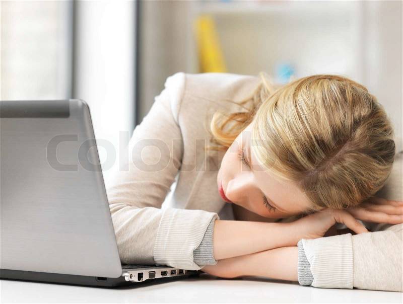 Indoor picture of bored and tired woman sleeping on the table, stock photo