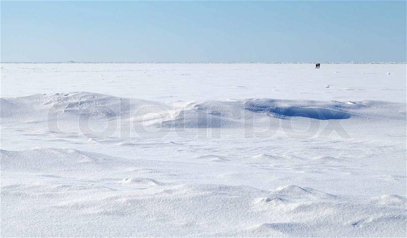 Winter landscape. Deep blue sky and snow on frozen Baltic Sea with people walking on ice, stock photo