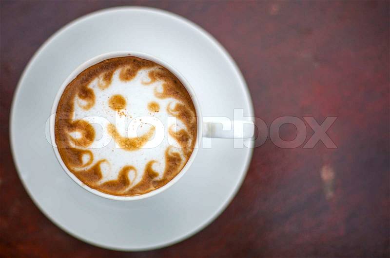 Cup of cappuccino with smiley face on wood table, stock photo