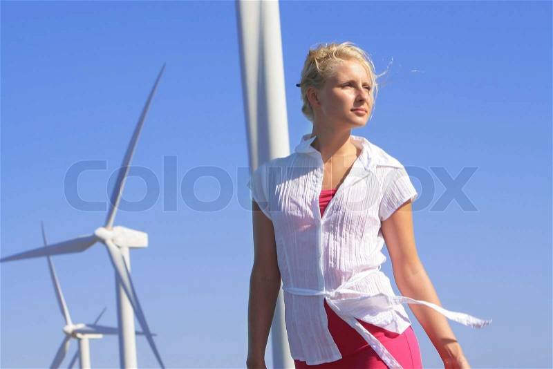 Young woman dreams about the future on a wind farm beneath eolic generator , stock photo