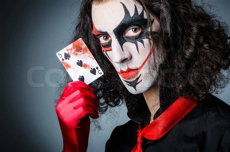 Evil clown with cards in dark room, stock photo
