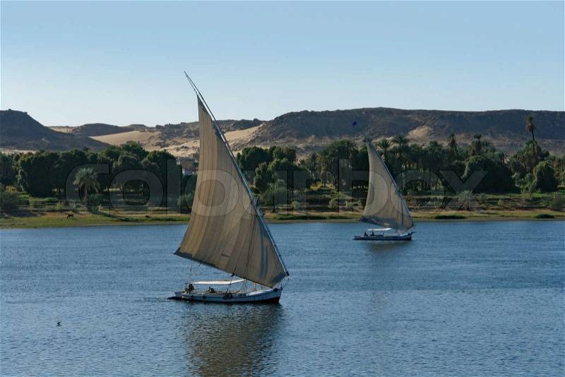 Waterside scenery at River Nile in Egypt Africa including two sailing boats, stock photo