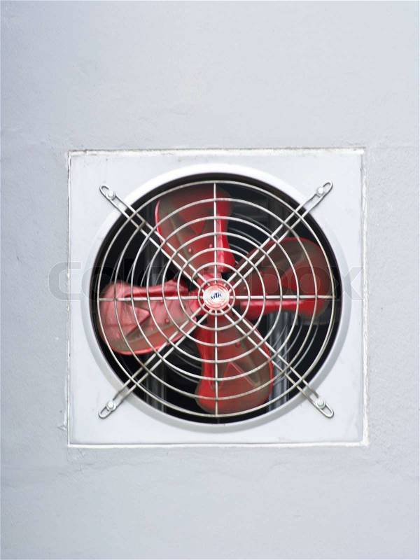 A red industrial ventilated fan on grey wall as background, stock photo