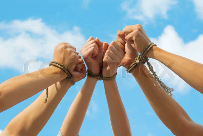 Three pairs of human hands tied up together with rope, stock photo