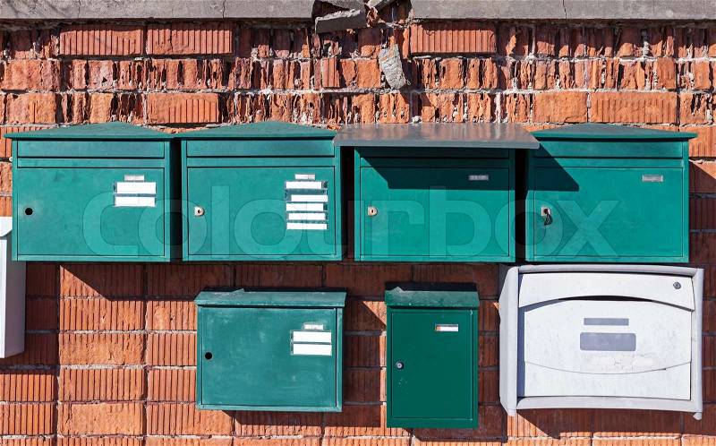 Green European metal post boxes on old brick wall, stock photo