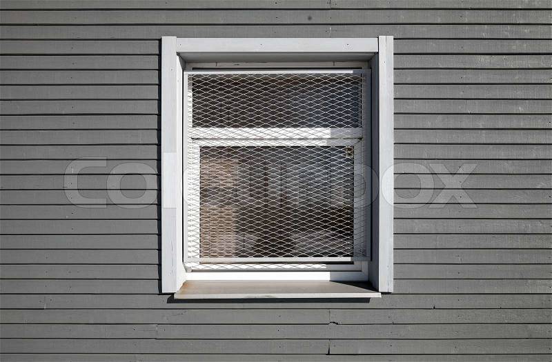 Texture of a locked window with metal grid on the gray wooden wall, stock photo