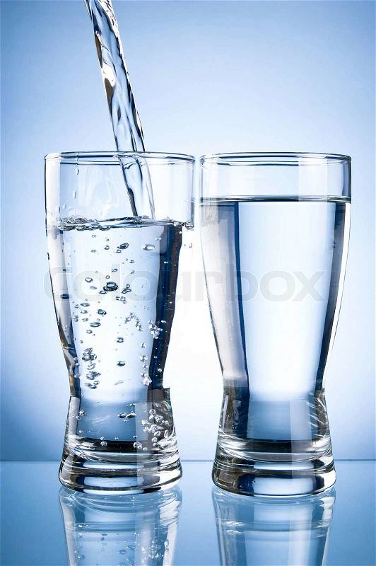 Pouring water into glasson and Glass of water on a blue background, stock photo